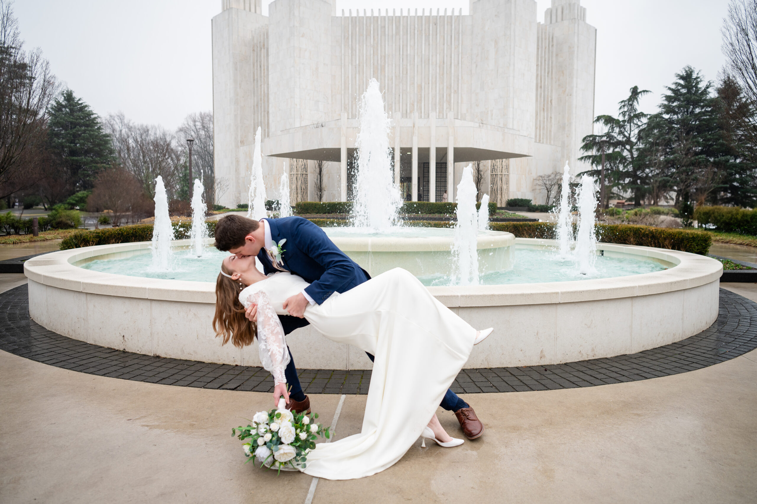 Groom In Navy Suit Dips And Kisses His Bride In White Dress